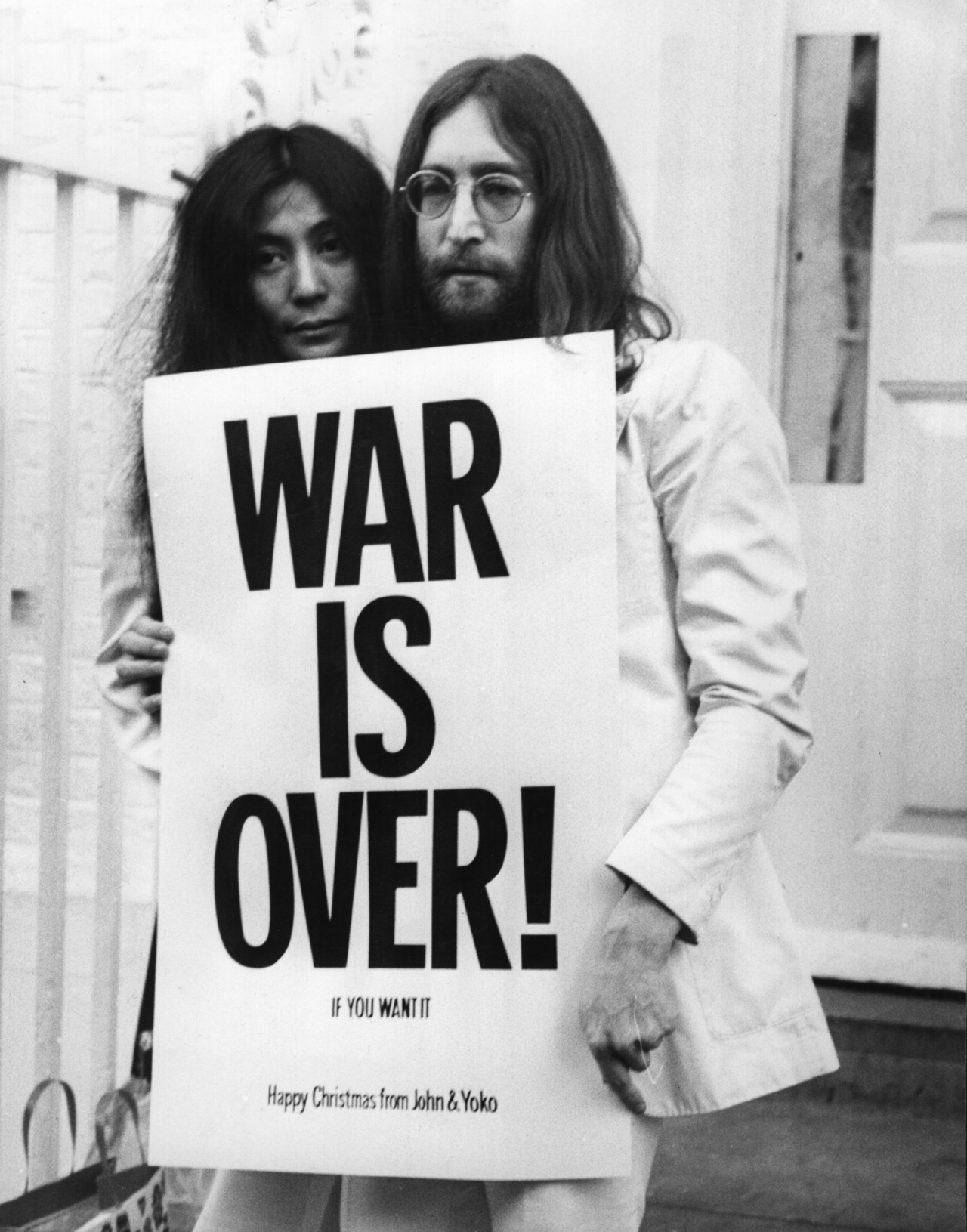 John Lennon (1940 - 1980) and Yoko Ono pose on the steps of the Apple building in London, holding one of the posters that they distributed to the world's major cities as part of a peace campaign protesting against the Vietnam War. 'War Is Over, If You Want It'. (Photo by Frank Barratt/Getty Images)